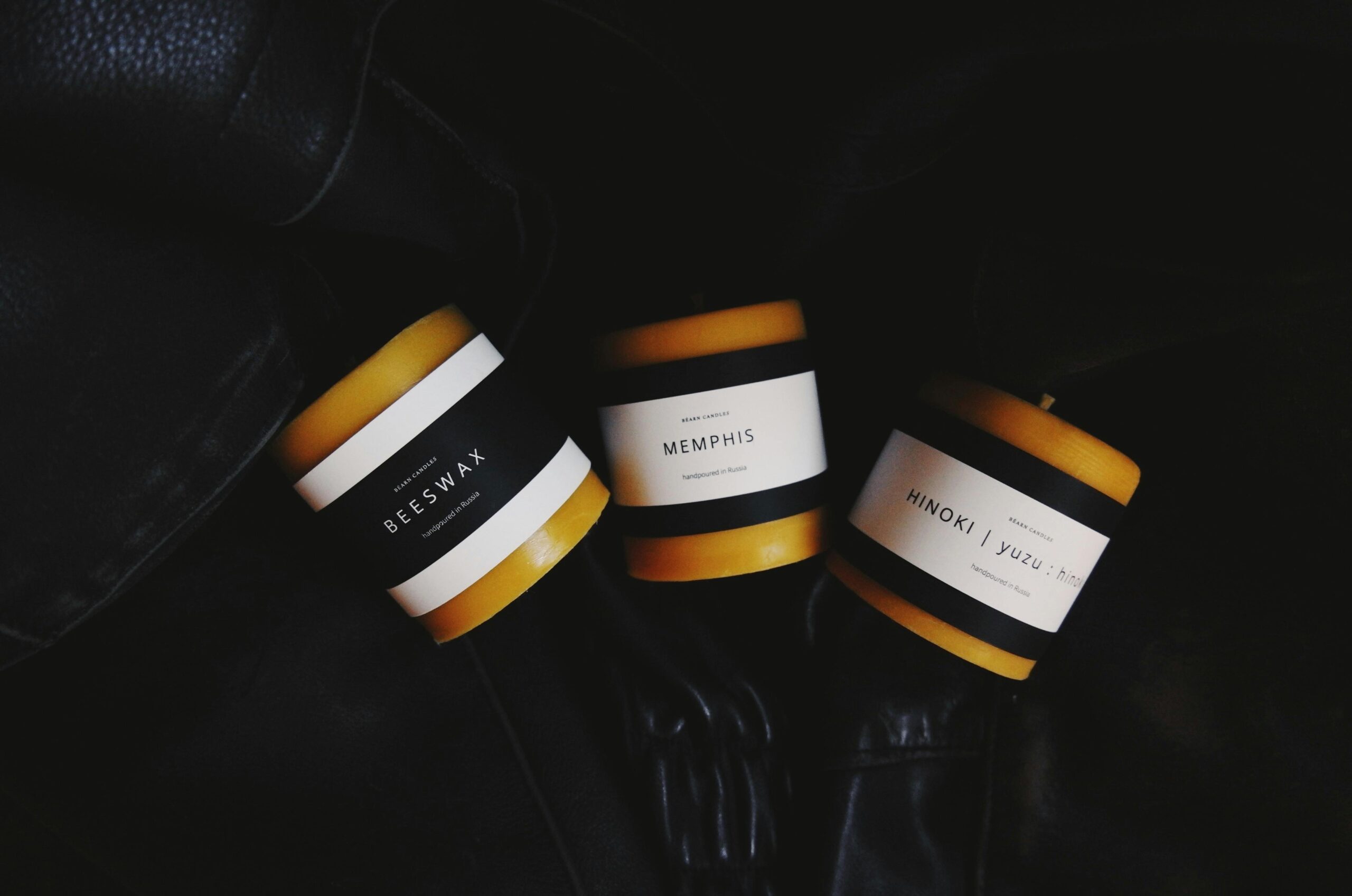 Eleganckie świece na czarnym tle z eleganckimi etykietami tworzą nowoczesną estetykę.