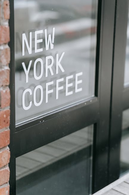 Close-up of a modern coffee shop entrance with New York Coffee sign on glass door.